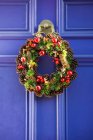 Corona decorativa de Navidad en una puerta azul de la casa; Londres, Inglaterra - foto de stock