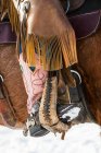 Rosafarbener Cowboystiefel eines Cowgirls im Steigbügel mit Lederchaps an der Seite eines Pferdes; Montana, Vereinigte Staaten von Amerika — Stockfoto