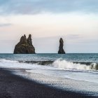 Кам'яні утворення вздовж берегової лінії Південного регіону Ісландії, з прибою, що промиває чорний пісок на передньому плані; Мюрдалшреппур, Південний регіон, Ісландія. — стокове фото