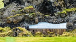 Амбар и сарай, построенный в скалистой горной местности, теперь заросшей травой; Rangarping eystra, Южный регион, Исландия — стоковое фото