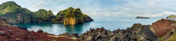 Rugged rock and cliffs along the coast of the island of Heimaey, a part of an archipelago along the Southern coast of Iceland; Vestmannaeyjar, Southern Region, Iceland - foto de stock
