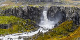 Wasserfall, der über eine Felswand fließt; Djupivogur, Östliche Region, Island — Stockfoto
