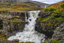 Waterfall and rushing river on a rugged landscape in Eastern Iceland; Djupivogur, Eastern Region, Iceland — Stock Photo