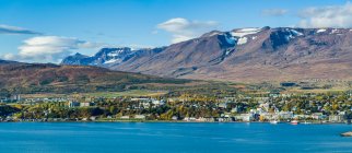 Stadt in Island mit strahlend blauem Wasser und Bergen mit Spuren von Schnee auf den Gipfeln; Island — Stockfoto