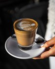 Cafe Latte con il disegno di arte del caffè che è tenuto dalla mano femminile; Melbourne, Victoria, Australia — Foto stock