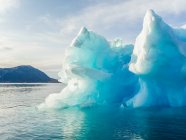 Um iceberg pinnacle ao longo da costa da Groenlândia em água azul brilhante; Sermersooq, Groenlândia — Fotografia de Stock