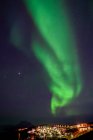 Северное сияние над освещенным городом в Гренландии; Гренландия — стоковое фото