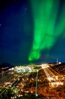 Nordlichter über einer beleuchteten Stadt in Grönland; Grönland — Stockfoto