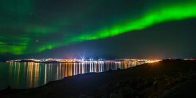 Северное сияние над светящимся городом Нуук; Нуук, Сермерсук, Гренландия — стоковое фото