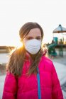 Молода дівчина стоїть на ігровому майданчику з захисною маскою для захисту від COVID-19 під час Всесвітньої пандемії Коронавірусу; Торонто, Онтаріо, Канада — стокове фото