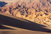 Huge sand dunes at sunset with desert mountains in the background; San Pedro de Atacama, Atacama, Chile — Stock Photo
