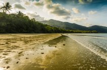 Late afternoon on an empty Australian beach with mountains and clouds in the background; Cape Tribulation, Queensland, Australia — Stock Photo