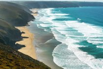 Sandy beaches with surf along a grassy cliff shoreline with blue sky and clouds; Cornwall County, England — Stock Photo