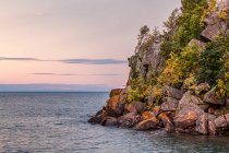 Lake Superior at sunset with rugged shoreline and autumn coloured foliage; Silver Bay, Minnesota, United States of America — Stock Photo