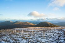 Wooden post fence on the top of a mountain in snow on a blue sky day, MacGillycuddy's Reeks; County Kerry, Ireland — Stock Photo