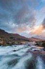White water river cascades through the Black Valley in the heart of the Kerry mountains at sunset, with a dramatic sky; County Kerry, Ireland — Stock Photo