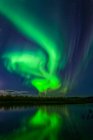 Aurora verde brilhante rodopiando sobre Harding Lake com reflexões, Interior Alaska no outono; Fairbanks, Alaska, Estados Unidos da América — Fotografia de Stock