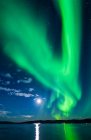 Leuchtend grüne Polarlichter mit Mondflammen über dem Harding Lake im Inneren Alaskas im Herbst; Fairbanks, Alaska, Vereinigte Staaten von Amerika — Stockfoto