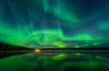 Яскраво-зелена полярна сяйво танцює над озером Бірч з віддзеркалюванням, Інтер'єр Аляска восени; Фербенкс, Аляска, США — стокове фото
