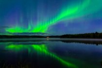 Aurora verde brilhante dançando sobre Birch Lake com reflexões, Interior Alaska no outono; Fairbanks, Alaska, Estados Unidos da América — Fotografia de Stock