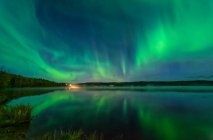Leuchtend grüne Polarlichter spiegeln sich im Herbst am Birch Lake im Landesinneren Alaskas; Fairbanks, Alaska, Vereinigte Staaten von Amerika — Stockfoto