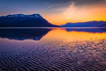 Coucher de soleil à Turnagain Arm of Cook Inlet. Un plat de marée ondulé se révèle à marée basse, les monts Chugach en arrière-plan. Centre-sud de l'Alaska en été ; Portage, Alaska, États-Unis d'Amérique — Photo de stock