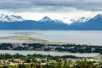 Aerial view of the city of Homer and the Homer Spit in Kenai Peninsula Borough, in Kachemak Bay with the Kenai Mountain Range in the distance; Kenai Peninsula, Alaska, United States of America — Stock Photo