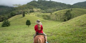 Una chica montando a caballo por las colinas; Zacapa, Guatemala - foto de stock