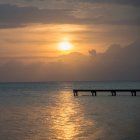 Silhueta de uma doca que conduz à água com o pôr do sol em um céu dramático; Utila, Ilhas da Baía, Honduras — Fotografia de Stock