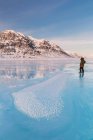 Man In A Parka Standing On Overflow Ice On The Frozen Anaktuvuk River, Hoar Frost Crystals In The Foreground, Napaktualuit Mountain In The Background, Gates Of The Arctic National Park; Alaska, Estados Unidos de América - foto de stock