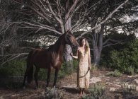 Mujer de pie con un caballo; Tarifa, Cádiz, Andalucía, España - foto de stock