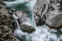 Blaues Wasser stürzt in einem rauschenden Fluss über Felsen, Haast Pass, Mount Aspiring National Park, Südinsel; Westküstenregion, Neuseeland — Stockfoto