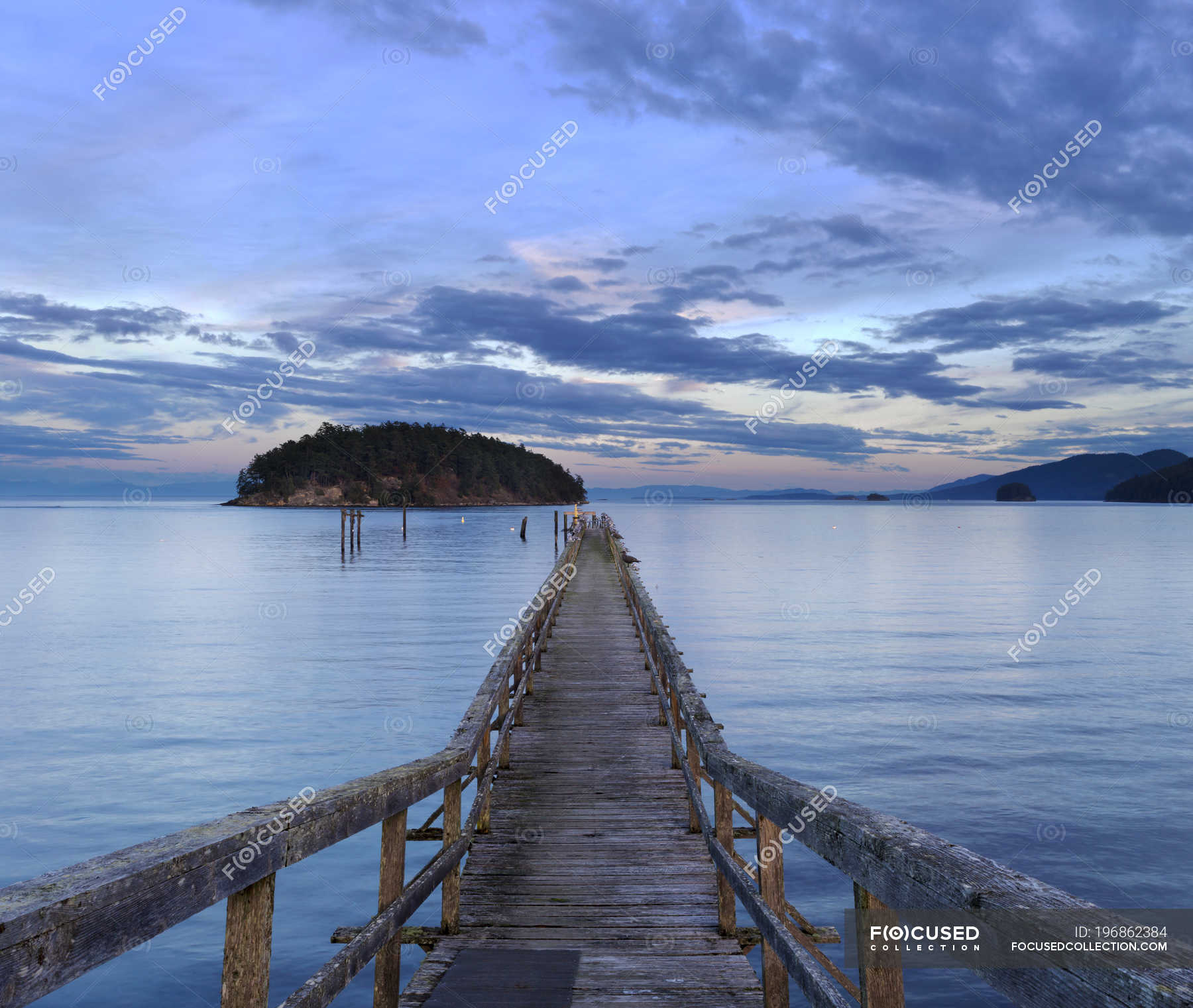 A wooden pier leading out into Bennet Bay in the Gulf Islands at sunset ...