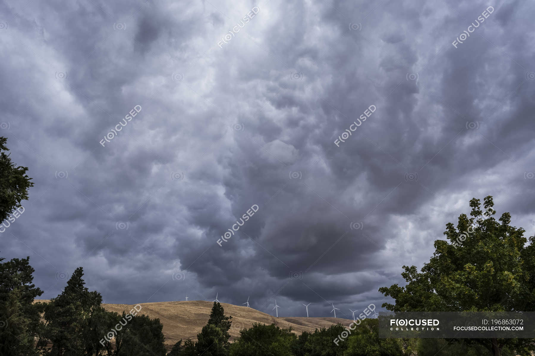 Dark clouds loom over Klickitat County with wind turbines on the hills