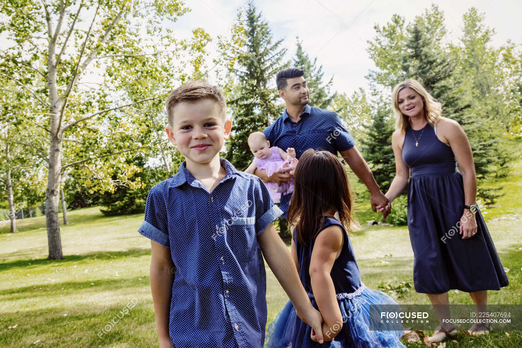 Mother And Father Walking With Kids In A Park Parenthood Husband Stock Photo