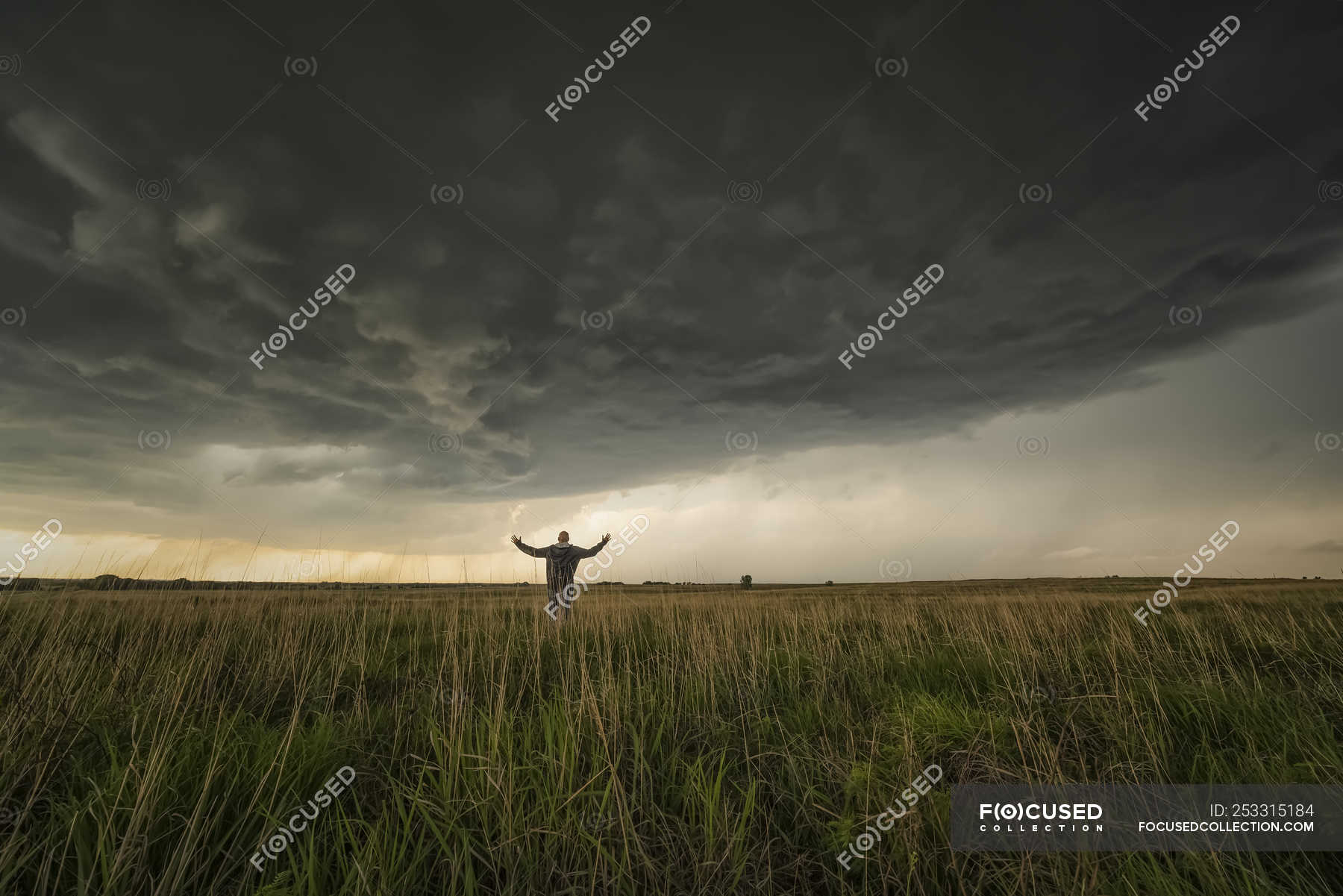 Man standing in the field watching the storm approaching; Kansas ...