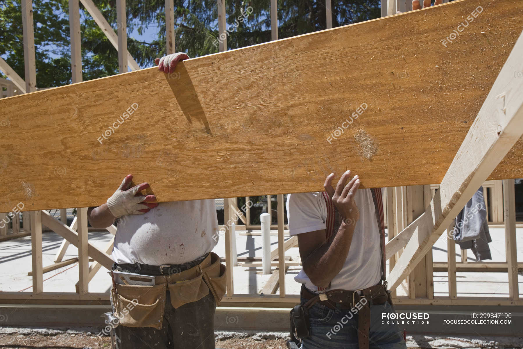 Carpenters lifting a laminated beam at a construction site — timber