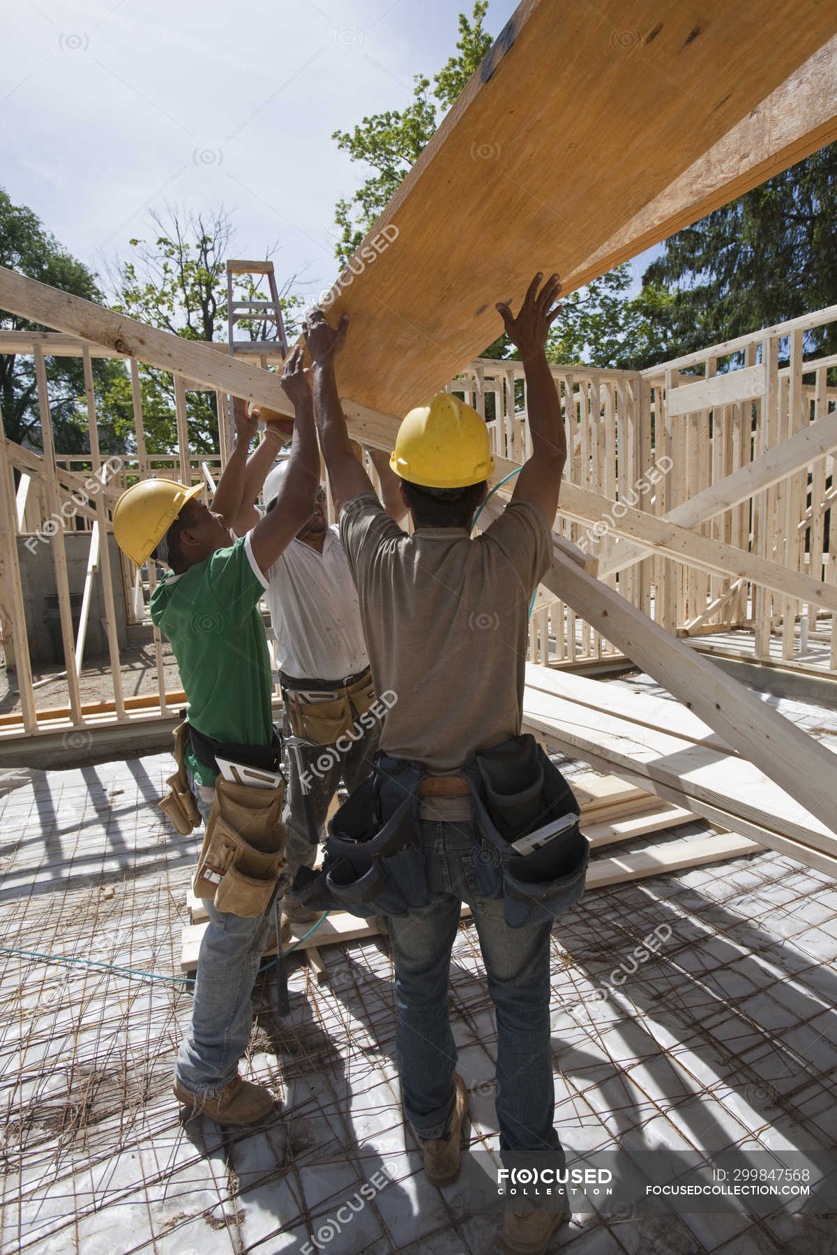 Carpenters lifting a laminated beam at a construction site — protection