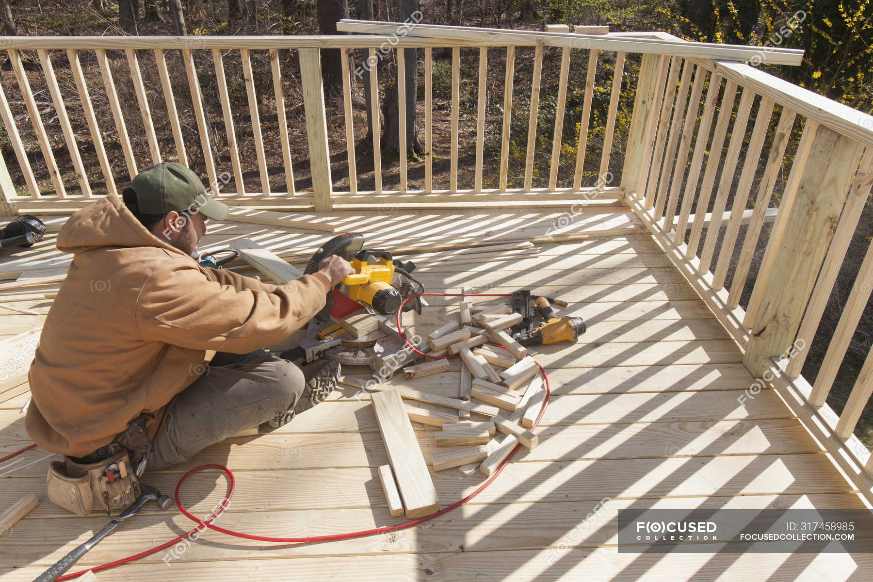 Hispanic carpenter using chop saw to cut deck railing cap — skill