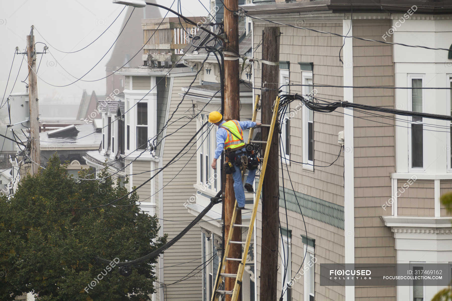Cable lineman assessing cable distribution wiring on poles in the city