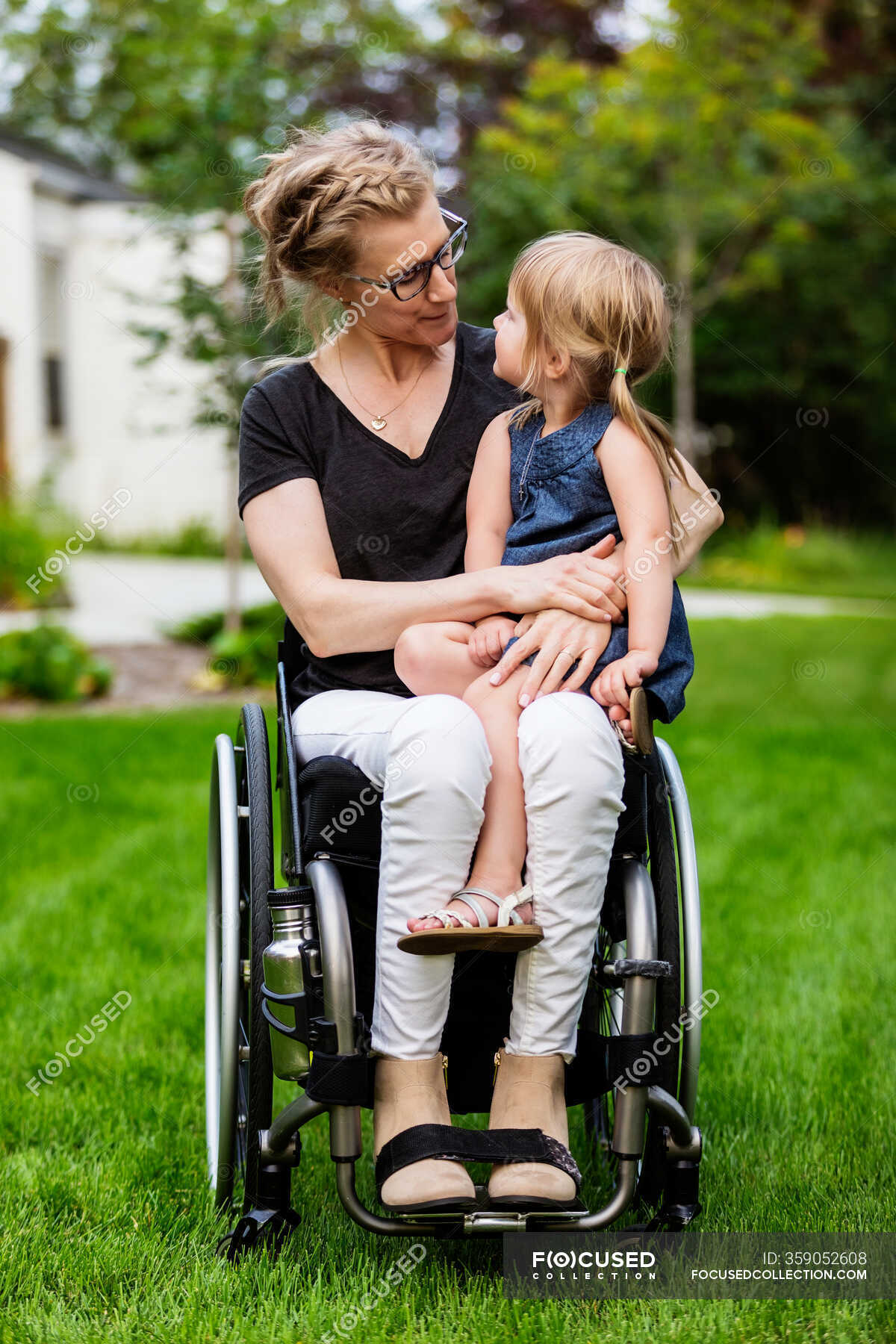 A paraplegic mom holding her little girl in her lap while sitting in