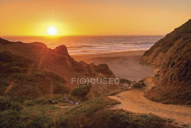 Coucher de soleil sur l'océan avec sentier jusqu'à la plage — Photo de stock