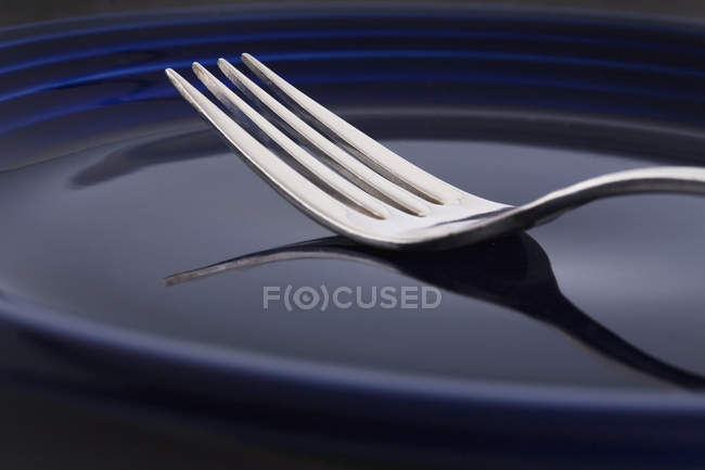 Closeup fork with reflection on blue plate — Stock Photo