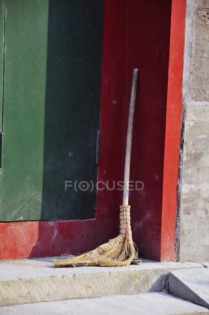 Old straw broom resting in the corner — Stock Photo