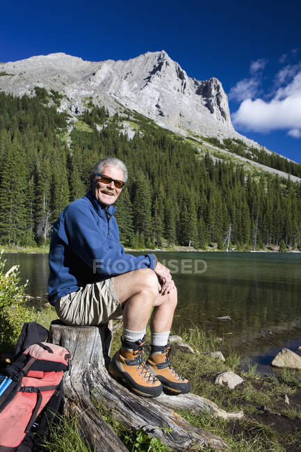 Мужчина-турист сидит на пне — стоковое фото