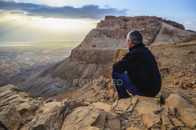 L'uomo siede su una roccia — Foto stock