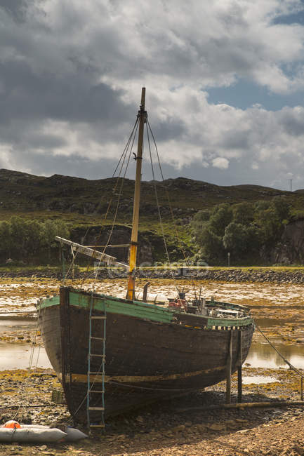 Barco sentado na costa na maré baixa — Fotografia de Stock