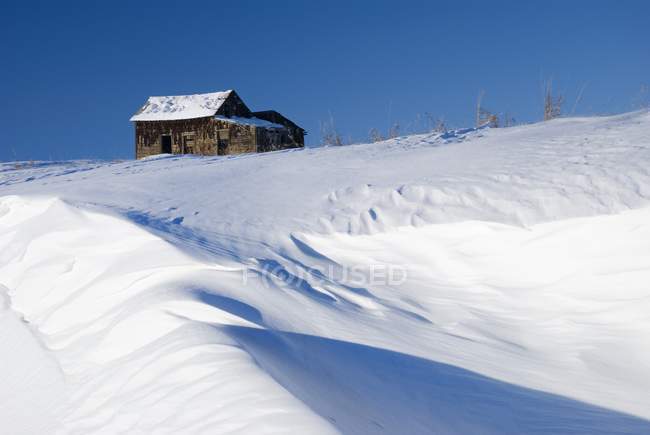 Edifício abandonado da fazenda no topo de uma colina nevada — Fotografia de Stock