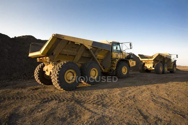 Vista de caminhões duro no trabalho sobre a areia — Fotografia de Stock