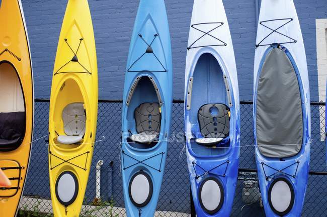 Kayaks coloridos apilados contra la pared - foto de stock
